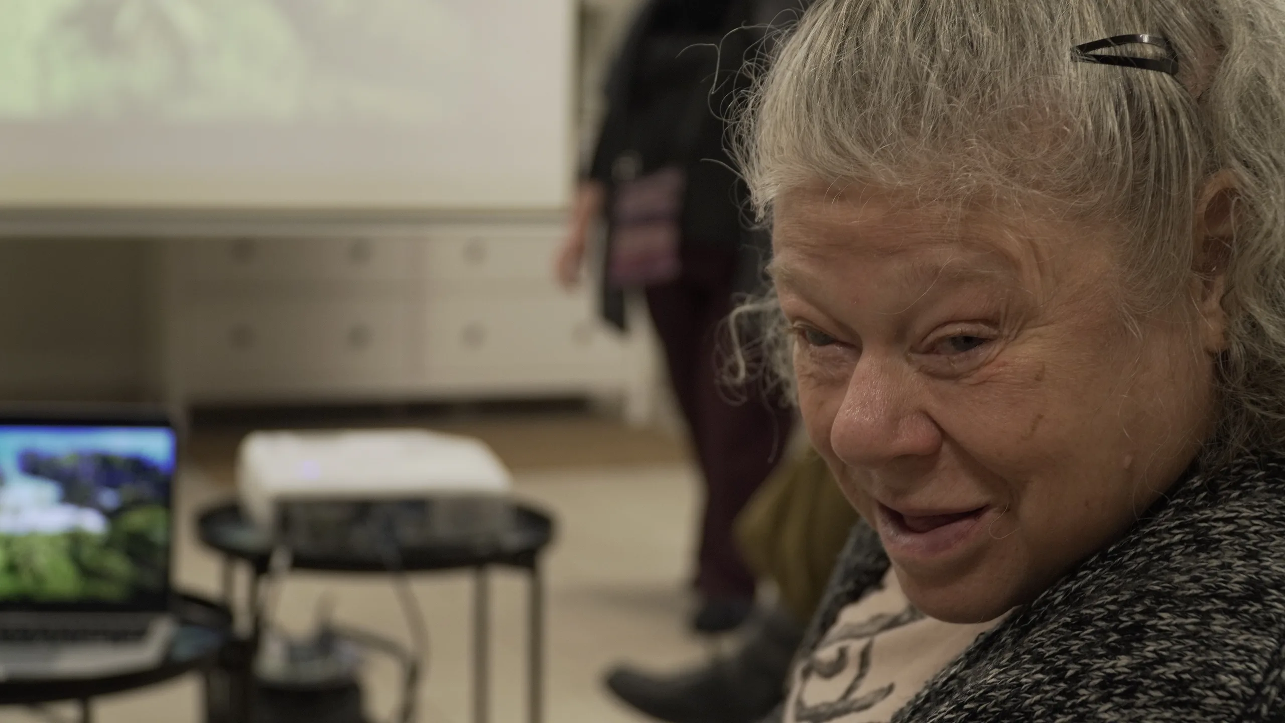 Une participante sourit au premier plan d'une salle équipée d'un vidéoprojecteur