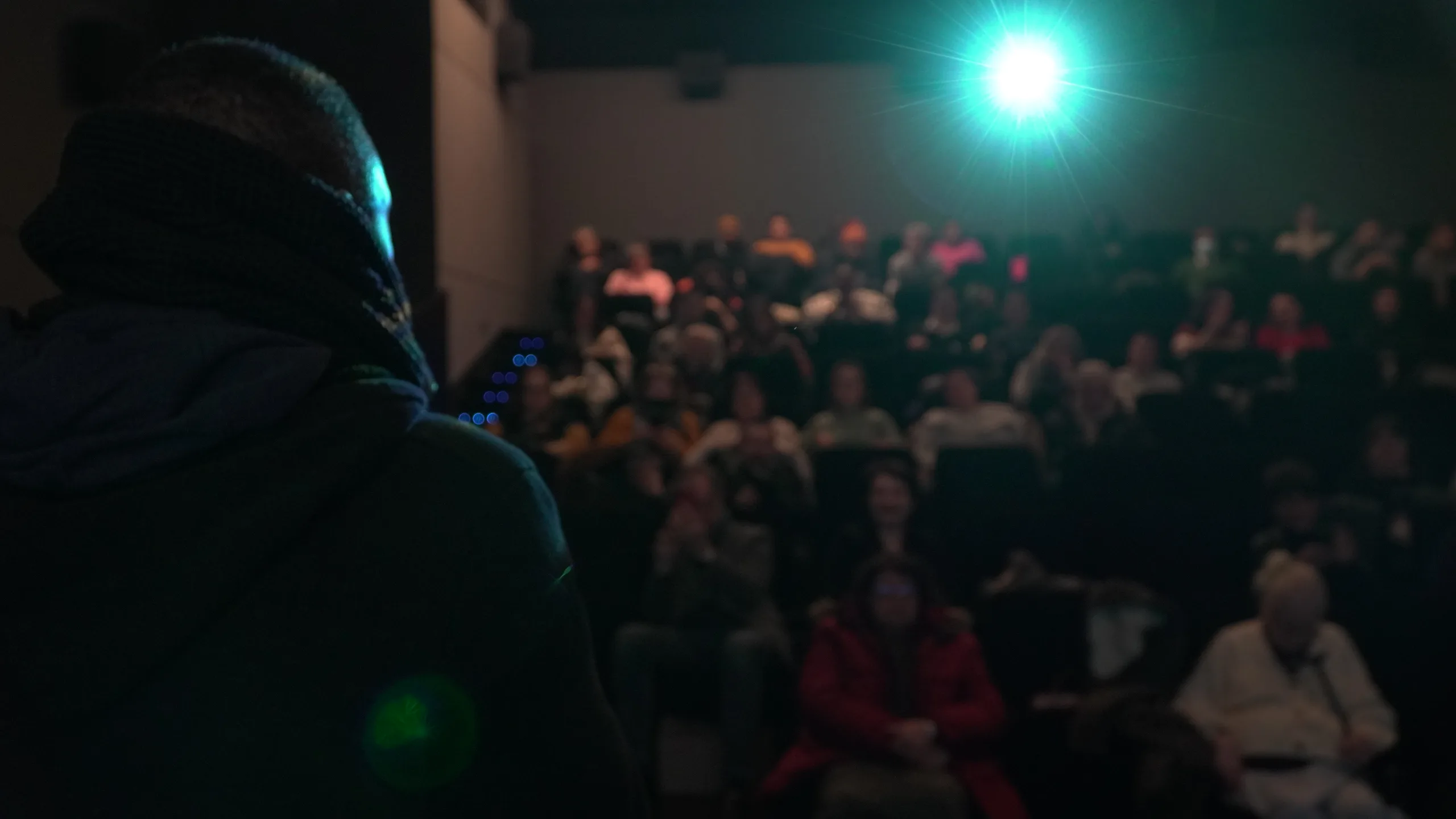 Projection d'un film BaKa en salle : le public installé face à l'écran, sous le faisceau du projecteur